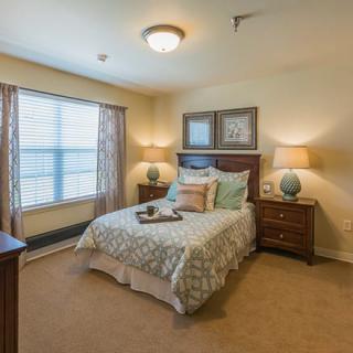 Cozy bedroom with a neatly made bed, bedside tables, and natural light.