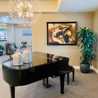 A stylish living room featuring a grand piano, elegant chandelier, and framed artwork.