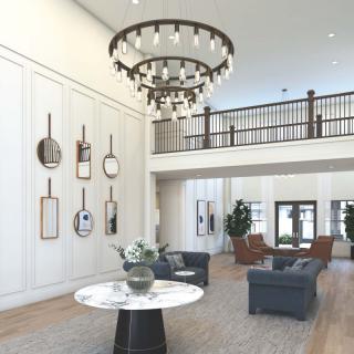 A modern lobby featuring a large chandelier, stylish seating, and decorative wall art.