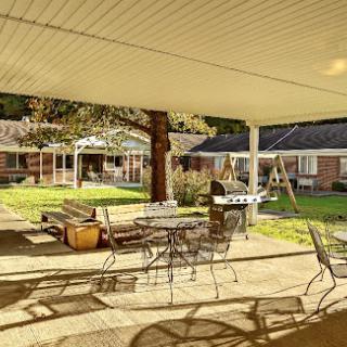 A serene outdoor patio area with seating, surrounded by greenery.