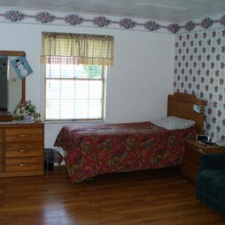 A cozy bedroom with a single bed, dresser, and window letting in natural light.