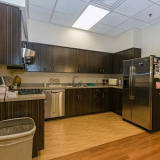 A modern kitchen with dark cabinets and stainless steel appliances.