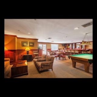 A cozy living room with a pool table, wood paneling, and comfortable seating.