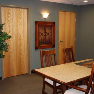 A conference room featuring a large table, chairs, wooden doors, and wall art.