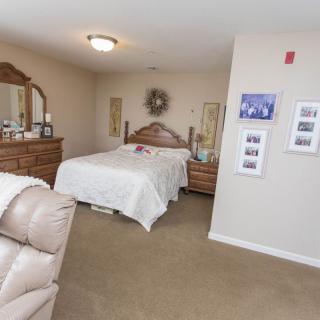A cozy bedroom with a neatly made bed and wooden furniture, including a dresser with a mirror.