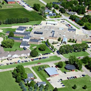 Aerial view of a school campus surrounded by lush greenery and parking areas.