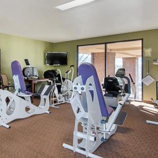 A small gym with exercise equipment, including workout machines and a TV.
