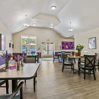 A bright and welcoming dining area with tables and chairs, featuring wood flooring and modern decor.