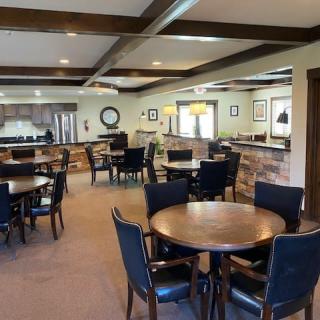 A modern dining area with multiple tables, chairs, and a kitchen in the background.