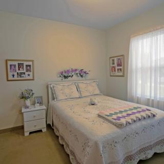 A cozy bedroom with a floral-themed decor, featuring a neatly made bed and soft lighting.