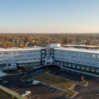 Aerial view of a large building with a surrounding parking lot in a suburban area.