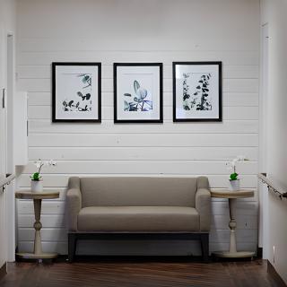 A cozy waiting area with a sofa and framed artwork on the wall.