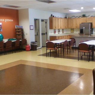A community kitchen and dining area with tables, chairs, and wooden cabinets.