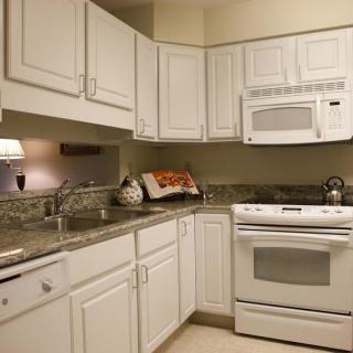 A modern kitchen with white cabinets and built-in appliances.