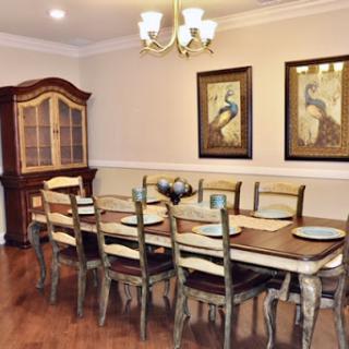 A stylish dining room featuring a long wooden table surrounded by chairs, complemented by elegant wall art and a chandelier.