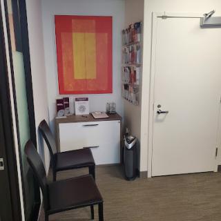 A modern waiting area featuring two chairs, an abstract artwork, and a neatly organized space.