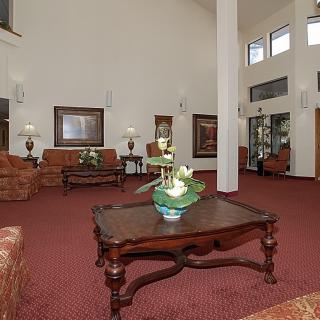 A spacious hotel lobby with elegant furniture, featuring a seating area and decorative elements.