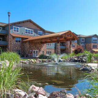 A modern residential building with a landscaped pond in the foreground.