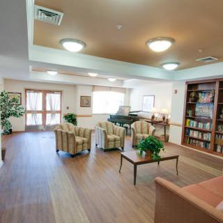 A cozy lounge area with comfortable seating, a piano, and a well-stocked bookshelf.