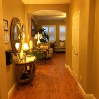 A warmly lit hallway leading to a cozy living room, featuring elegant furniture and decorative accents.