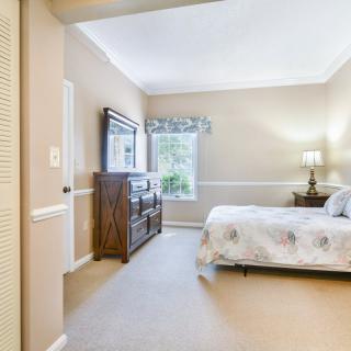 A cozy bedroom with a bed, dresser, and lamp by the window.