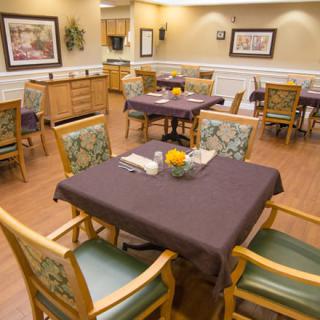A cozy dining area with neatly arranged tables and chairs, featuring warm lighting and tasteful decor.