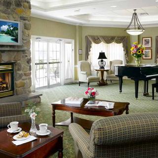 A cozy living room featuring a piano, fireplace, and elegant furnishings.
