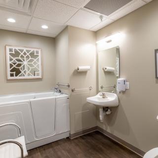 A modern, accessible bathroom with a walk-in bathtub and wall-mounted sink.
