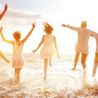 A group of friends enjoying a joyful moment at the beach during sunset.