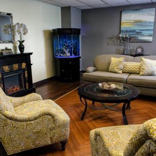A cozy living room featuring a sofa, armchairs, a coffee table, and an aquarium in the corner.