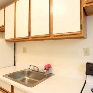A small kitchen area with a sink, white cabinets, and countertop appliances.