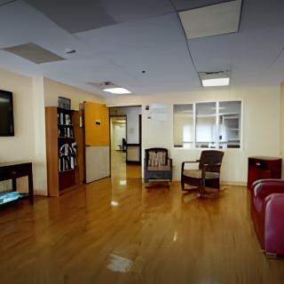 A spacious waiting room with wooden flooring, equipped with comfortable chairs and a sofa.