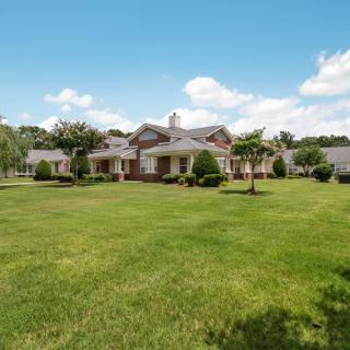 A picturesque suburban house with a large, well-maintained lawn under a clear blue sky.