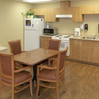 A modern kitchen with wooden cabinets, a dining table, and essential appliances.