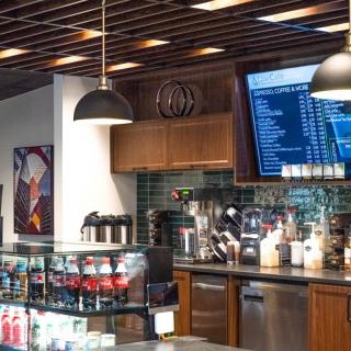 A modern coffee shop interior with a menu board and beverage counter.
