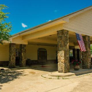 A welcoming entrance featuring stone pillars and an American flag against a bright blue sky.