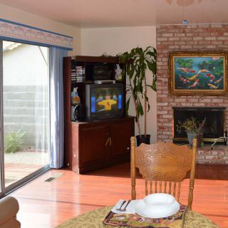 Cozy living room with a fireplace and television, featuring wooden furniture and a sliding glass door.