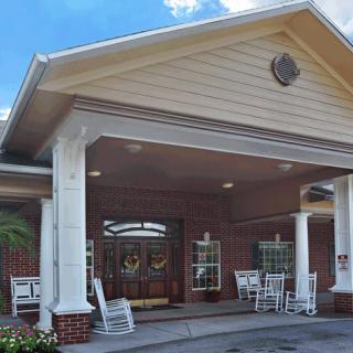 Front entrance of a building with a covered porch and rocking chairs.