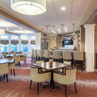 A modern restaurant interior with a bar and dining area featuring elegant seating and lighting.