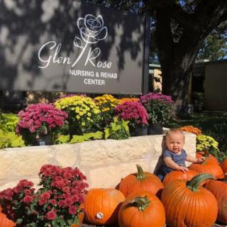 A joyful moment surrounded by pumpkins and vibrant flowers at Glen Rose Nursing & Rehab Center.