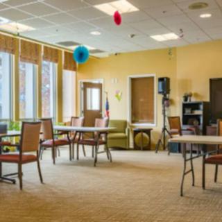 A spacious room with tables and chairs, decorated with balloons.