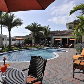 A tropical resort pool with lounge chairs and umbrellas under a clear sky.