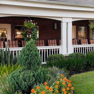 A charming porch with a beautifully landscaped garden featuring various flowers and shrubs.