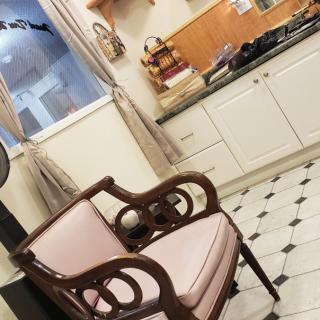 A cozy kitchen with a vintage chair and classic white cabinets.