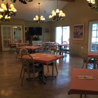 A cozy dining room with neatly arranged tables and elegant chandeliers.