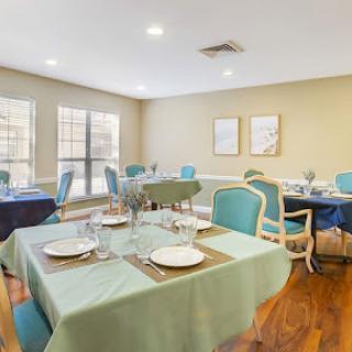 A stylish dining area featuring elegantly set tables with a calming green and blue color scheme.
