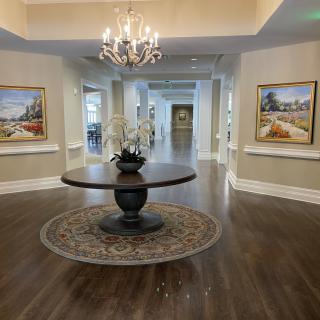 A luxurious lobby area featuring a central table, decorative artwork, and a chandelier.