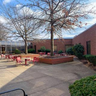 A tranquil courtyard featuring seating areas surrounded by trees and brick walls.