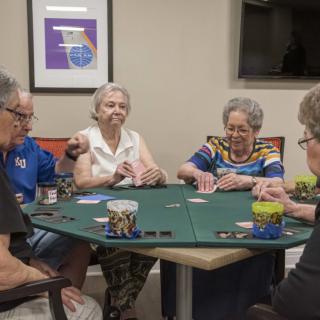 A group of elderly people playing cards at a table indoors.