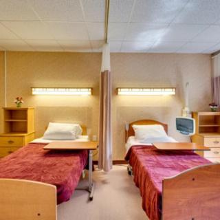 A shared hospital room with two beds and medical equipment.